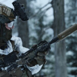 Vojak s puško pozimi v zimski kamuflažni opremi